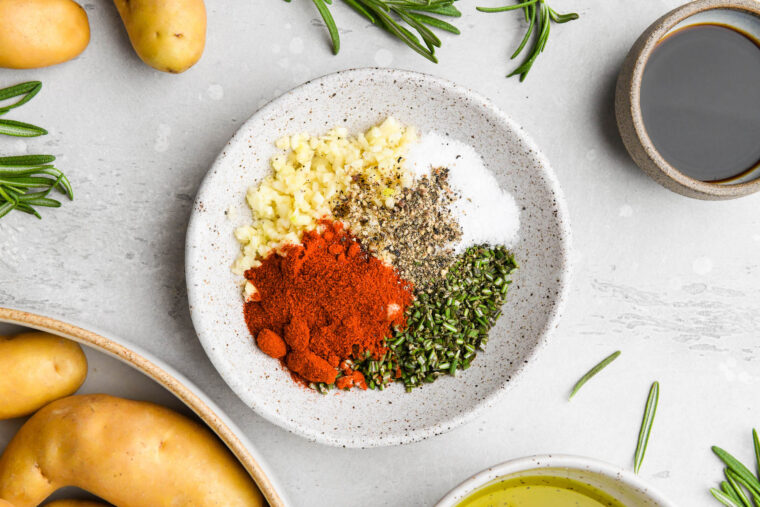 Several seasonings and aromatics in a white bowl before mixing together