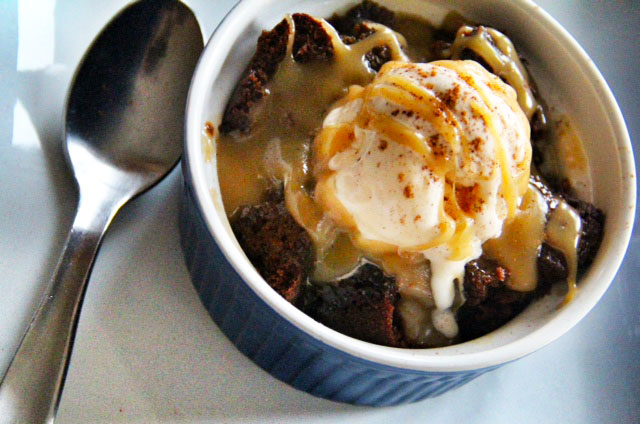 sticky toffee gingerbread bread pudding Close up of sticky toffee gingerbread bread pudding contained in a blue bowl with a silver spoon on the side.