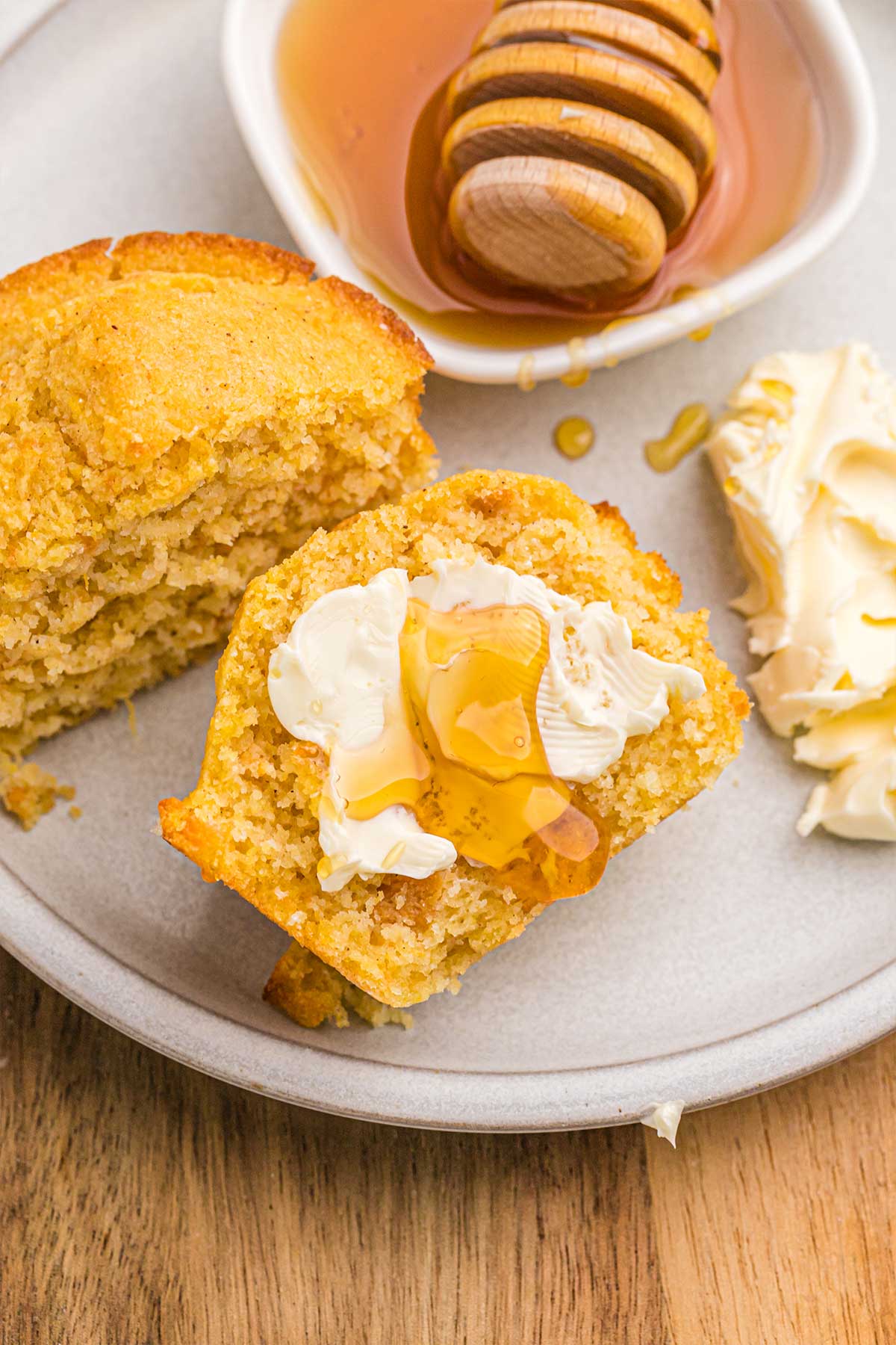 Sweet potato cornbread muffin split in half and topped with butter and honey.