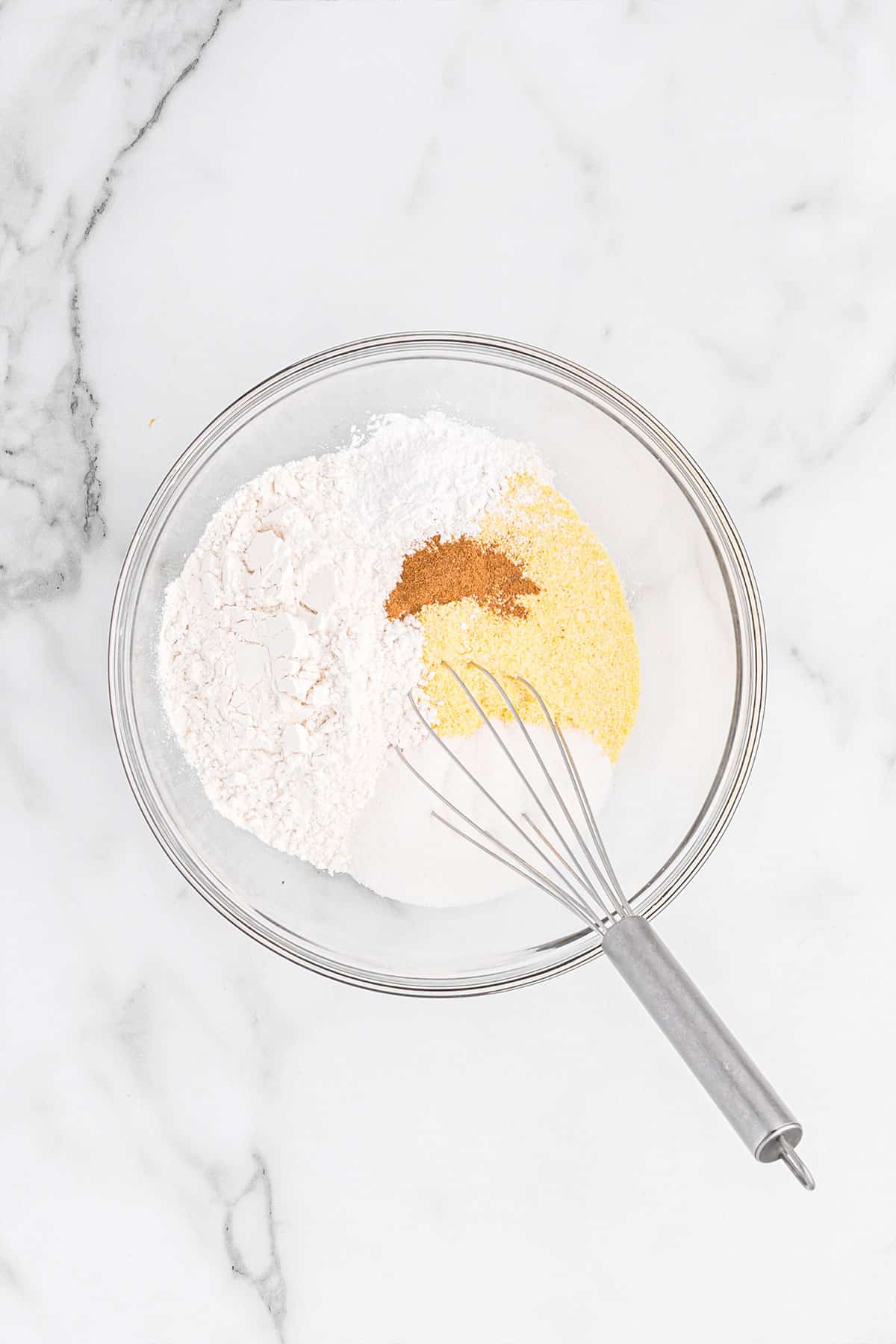 Dry ingredients in a mixing bowl with a whisk.